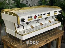 La machine à café expresso La Marzocco Linea Pb 4 Group avec poignées blanches et dorées pour café.